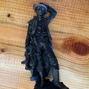 Western cowboy holding horse saddle statue